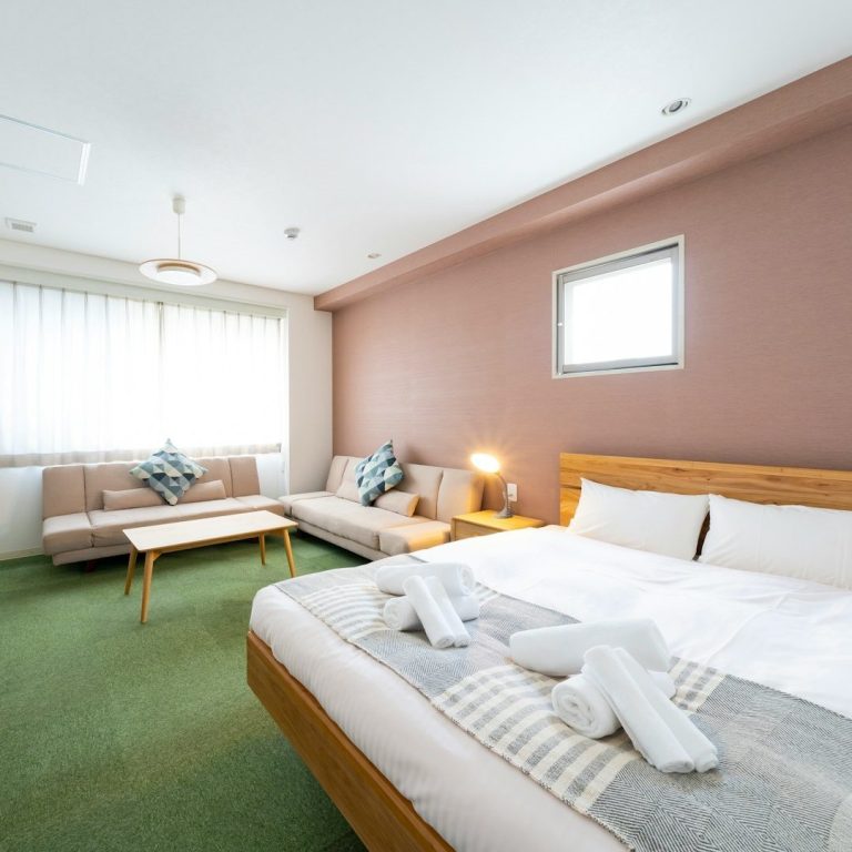 Kurzzeitvermietung Helles, modernes Hotelzimmer mit Doppelbett, Couch und Sitzbereich.